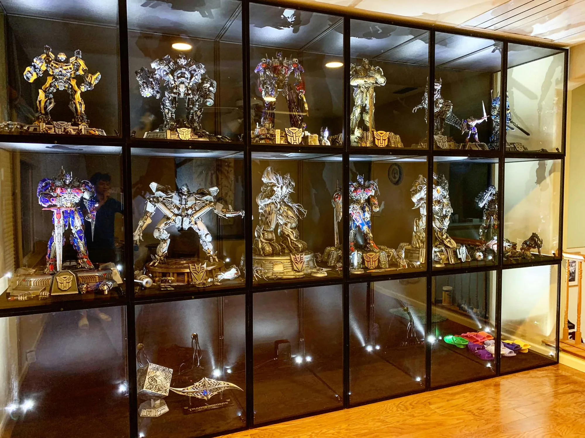Warm-lit wall of Transformers statues in Moducase Max Plus display cases